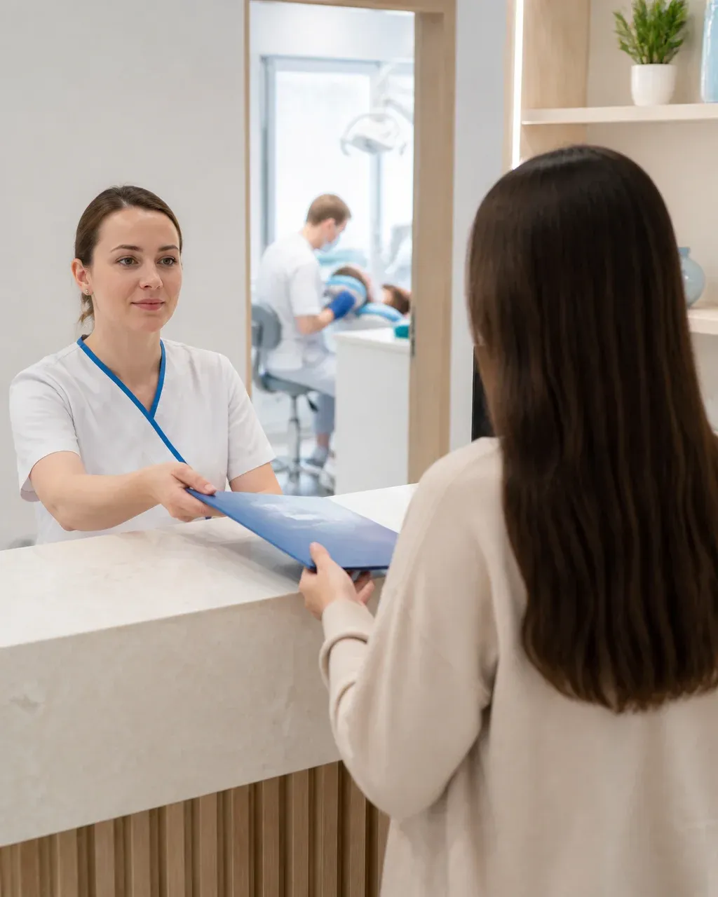 The clinic administrator gives the patient a treatment plan at the front desk
