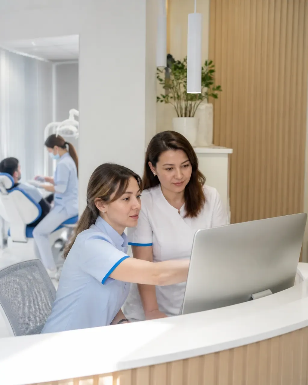 Clinic administrators check the appointment schedule on the screen at the front desk
