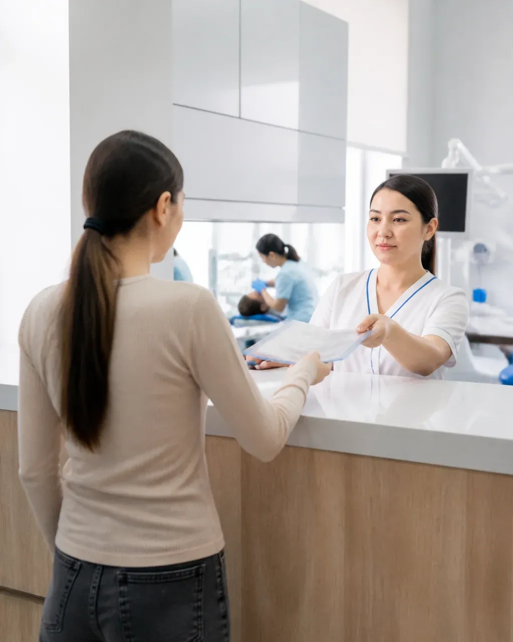The clinic administrator gives the patient a treatment plan at the front desk