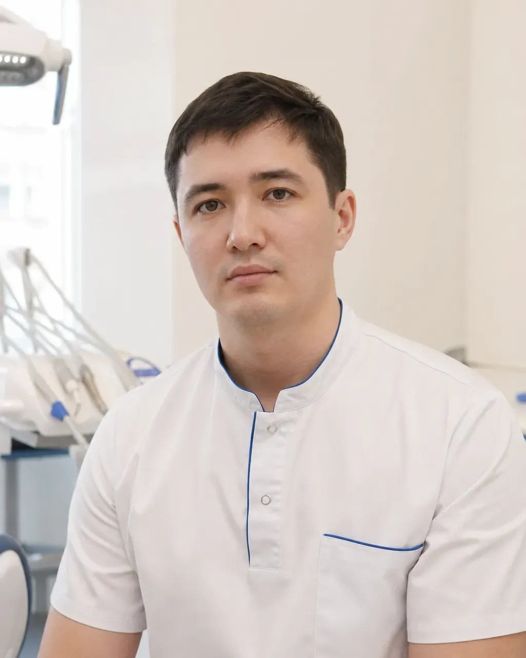 Ахметов Санжар Бауыржанұлы — Алматыдағы Dental-Center стоматологиялық клиникасының дәрігері, жұмыс киіміндегі портреті