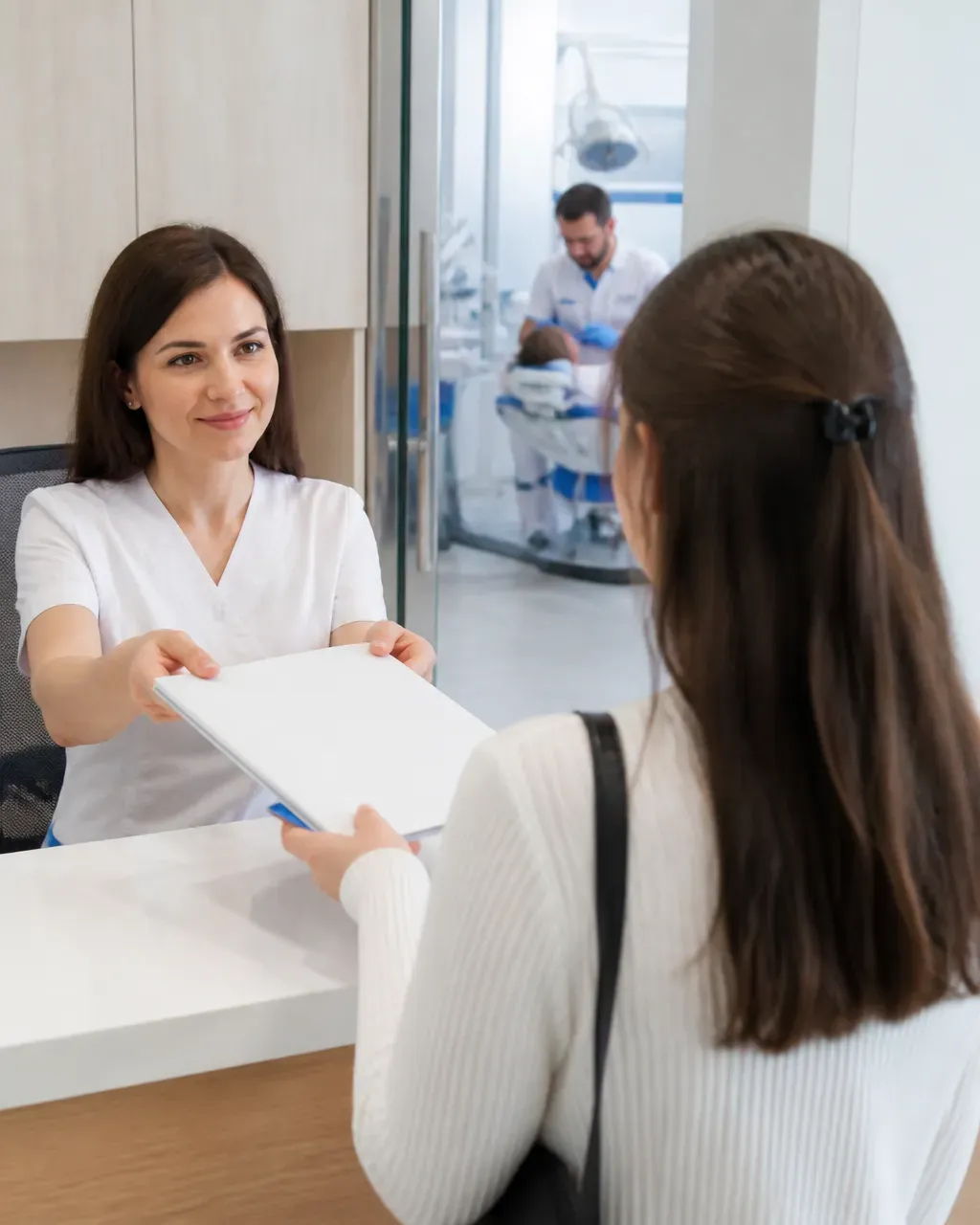 The clinic administrator gives the patient a treatment plan at the front desk
