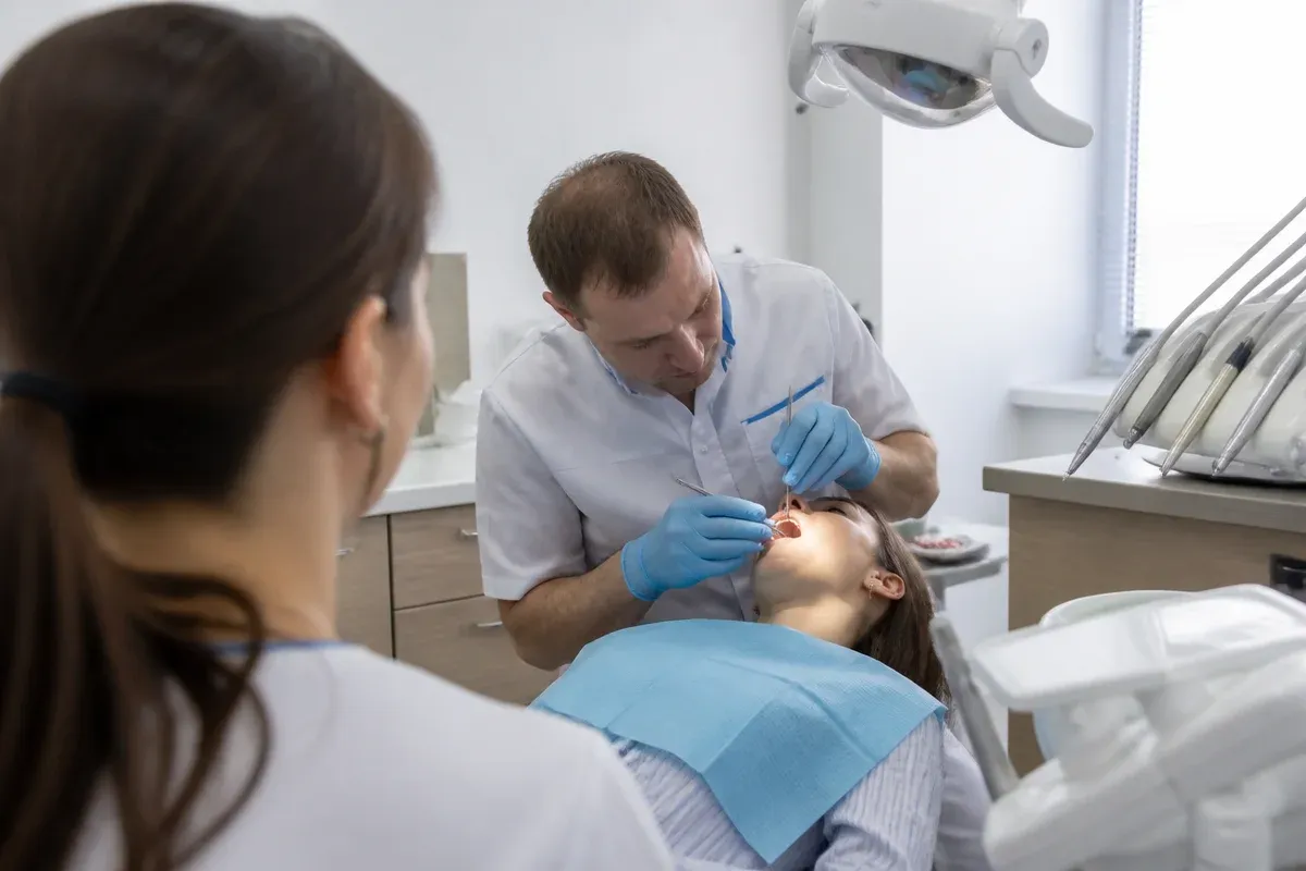 Креслодағы қабылдау: жұмыс үстіндегі дәрігер, ассистенттің иығынан түсірілген сурет — «Қорытпалар бір-бірінен қалай ерекшеленеді» бөліміне иллюстрация