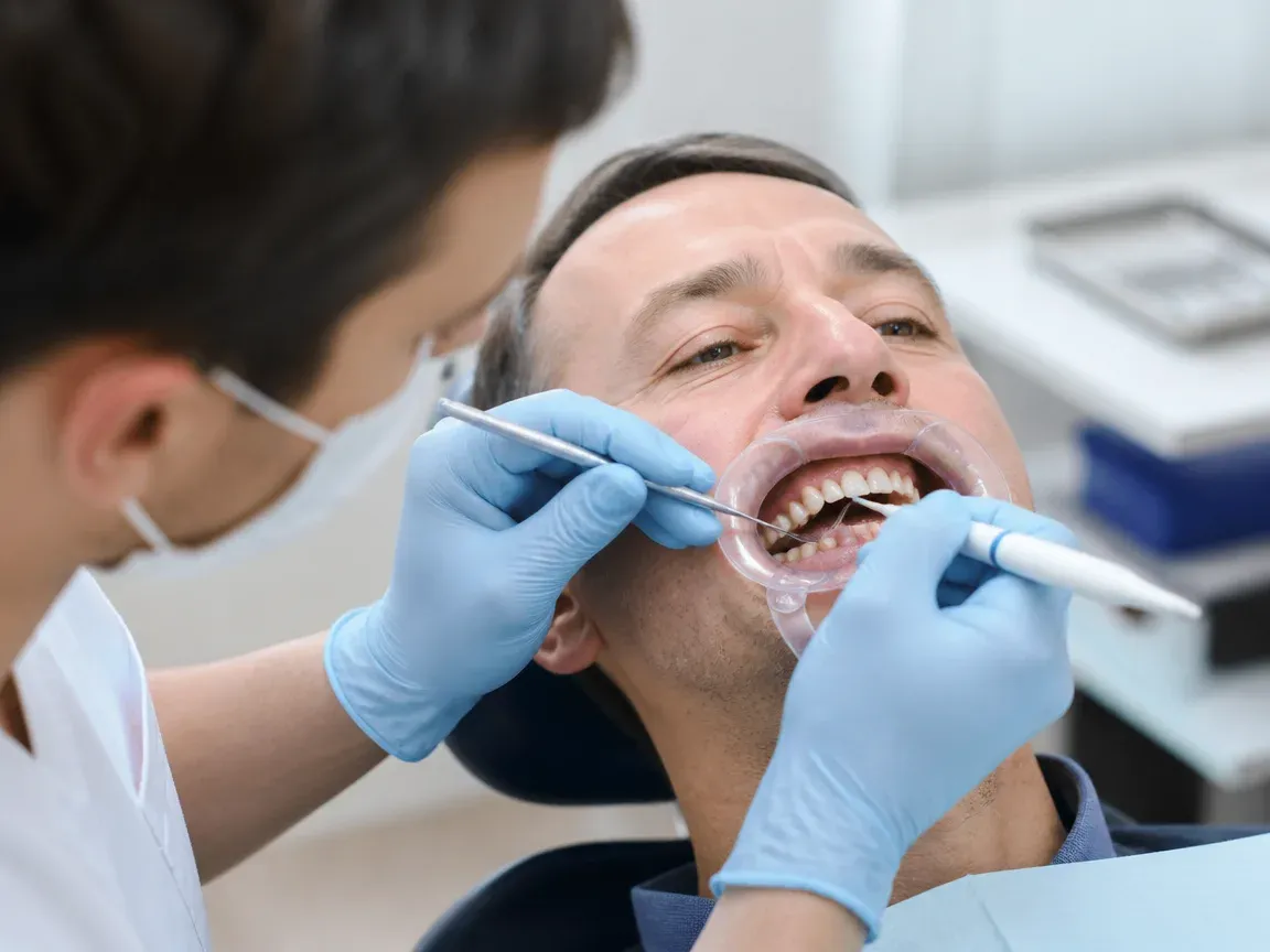 The treatment stage itself: the doctor's gloved hands working in the oral cavity — an illustration for the section "Preparing teeth and gums before prosthetics"