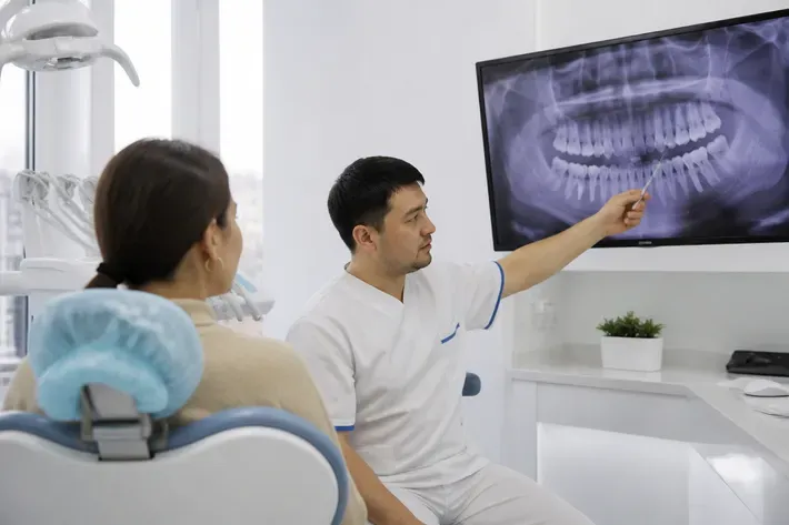 The doctor shows the patient the scan on the screen and explains the treatment plan — an illustration for the section "Removable and fixed dental bridges"