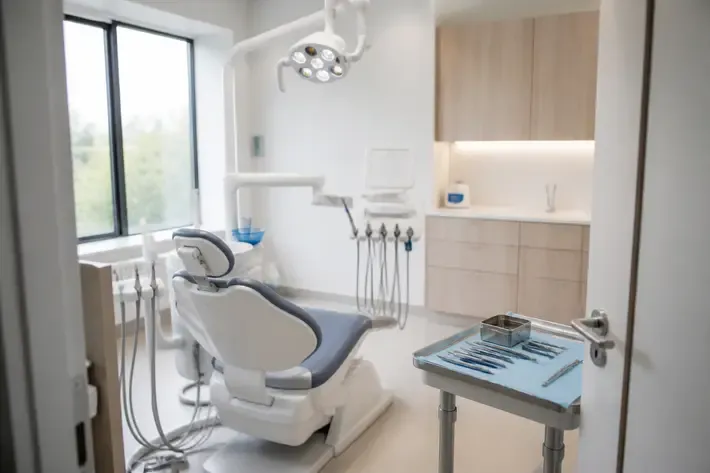 Treatment room prepared for a patient: dental chair, lamp, and tray of instruments — illustration for the Cystectomy section